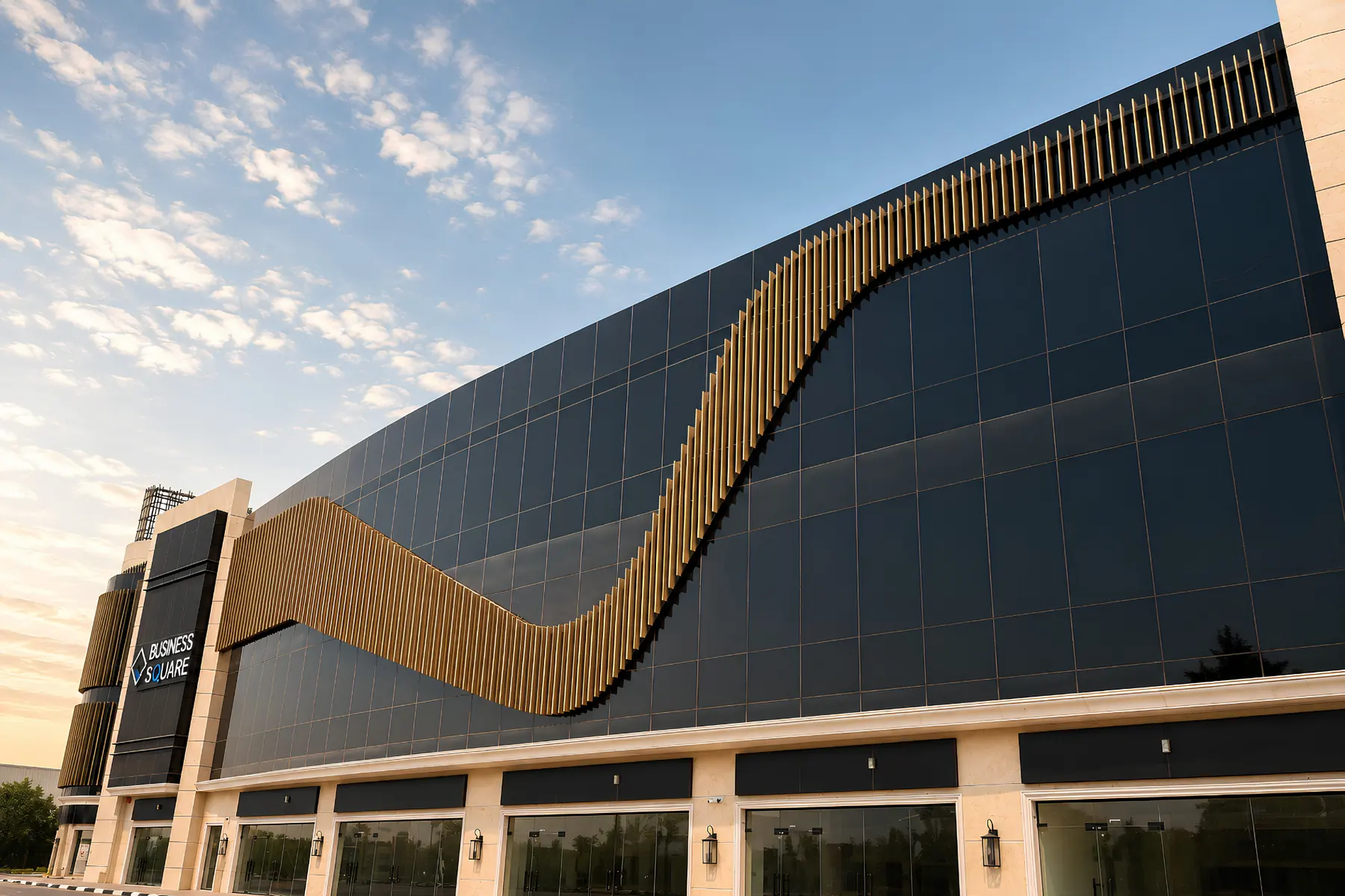 Business Square Ajman at dusk — dark metal cladding with a bronze fin ribbon