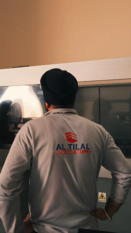 Machine operator in Al Tilal uniform working at a fabrication machine